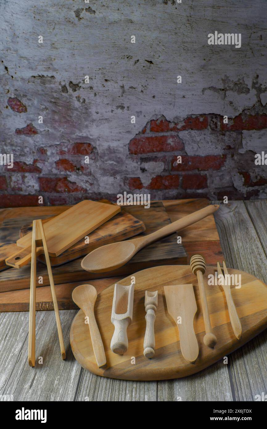 Vari tipi di utensili da cucina in legno su taglieri in legno con supporto a parete in mattoni Foto Stock