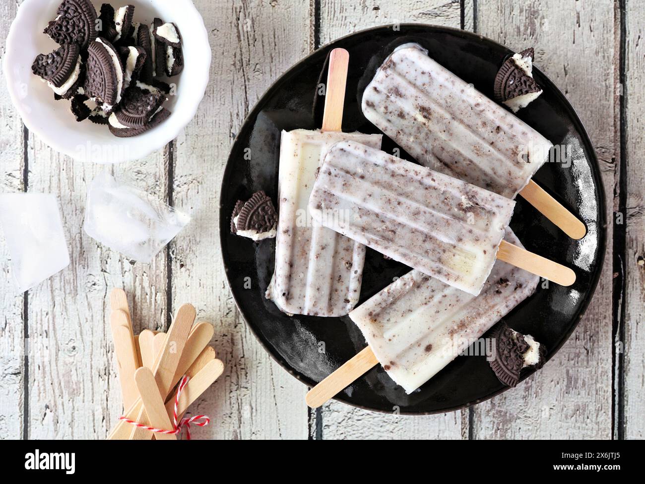 Biscotti e papaveri panna su un piatto nero. Vista dall'alto su sfondo di legno bianco. Foto Stock