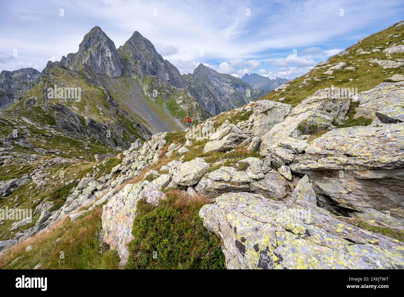 Alpinista su un sentiero escursionistico in sella, cime rocciose appuntite Letterspitze e Steinwand all'Obergailtaler Joch, Carnic Main Ridge Foto Stock