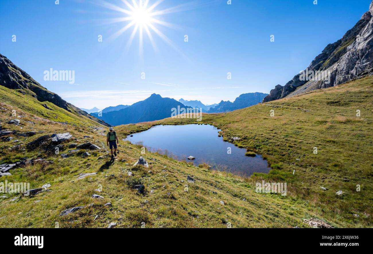 Alpinista presso un lago di montagna, Sonnenstern, Luggauer Toerl, Karnischer Hoehenweg, Karnischer Hauptkamm, Alpi Carniche, Carinzia, Austria Foto Stock
