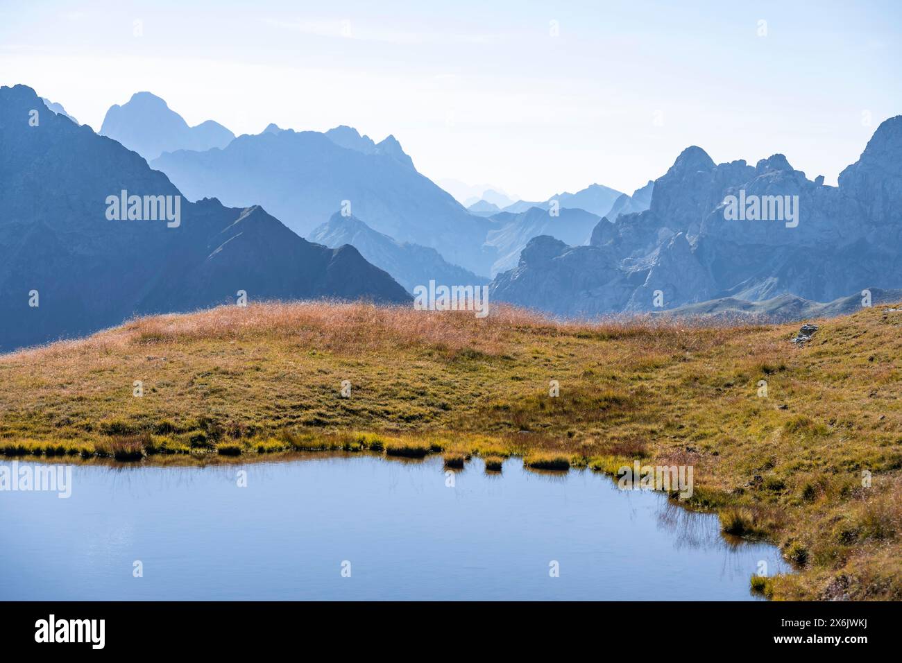 Lago di montagna di fronte al paesaggio montano, sagome di cime rocciose, Luggauer Toerl, Carnic High Trail, Carnic Main Ridge, Carnic Alps Foto Stock