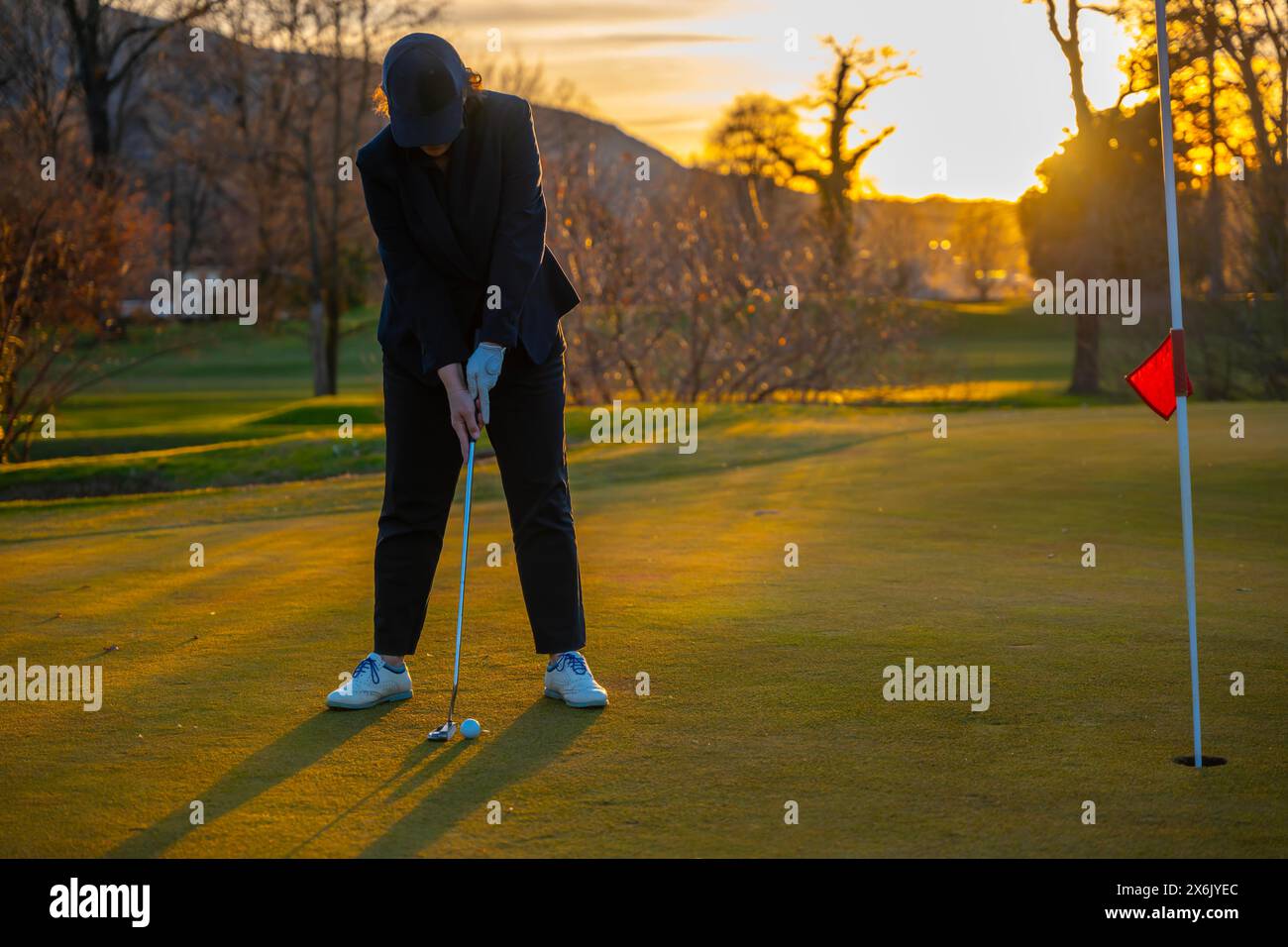 Giocatrice di golf al Putting Green on Golf Course di Sunset in Svizzera Foto Stock