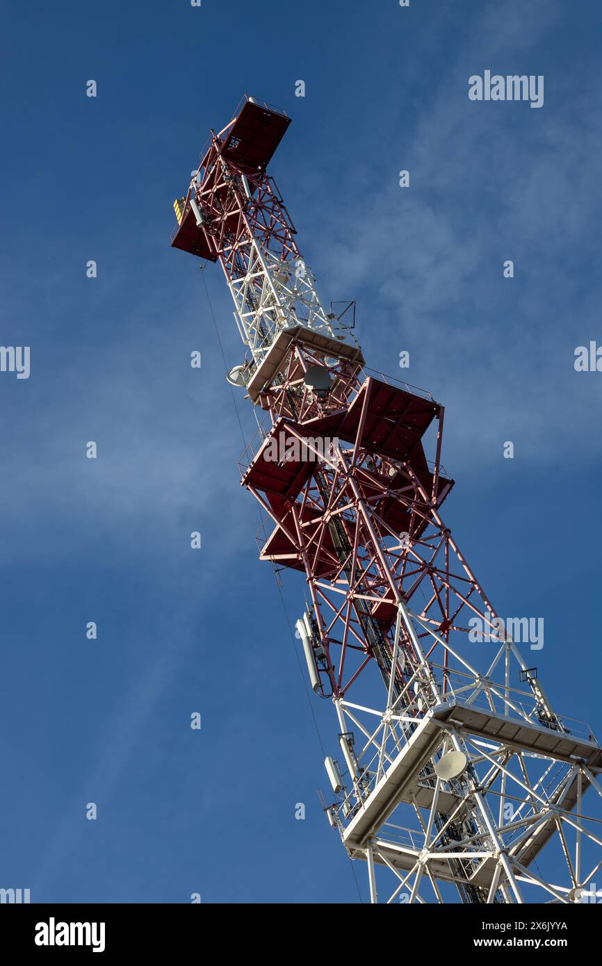 Antenna per telecomunicazioni per radio, televisione e telefonia con nuvola e cielo blu. Foto Stock