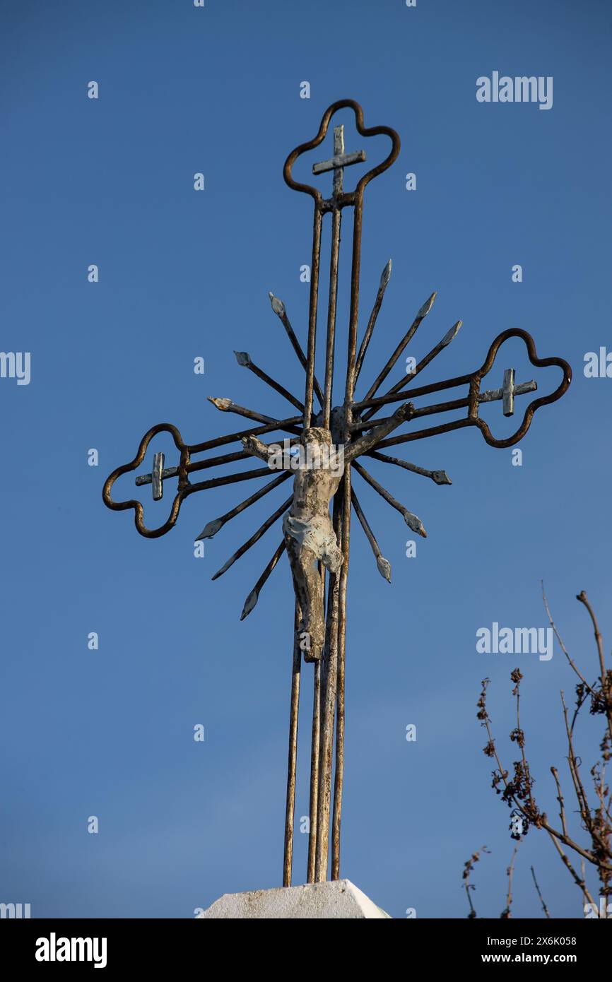 Vecchia croce di metallo con un crocifisso su uno sfondo cielo senza nuvole. Immagine verticale. Foto Stock