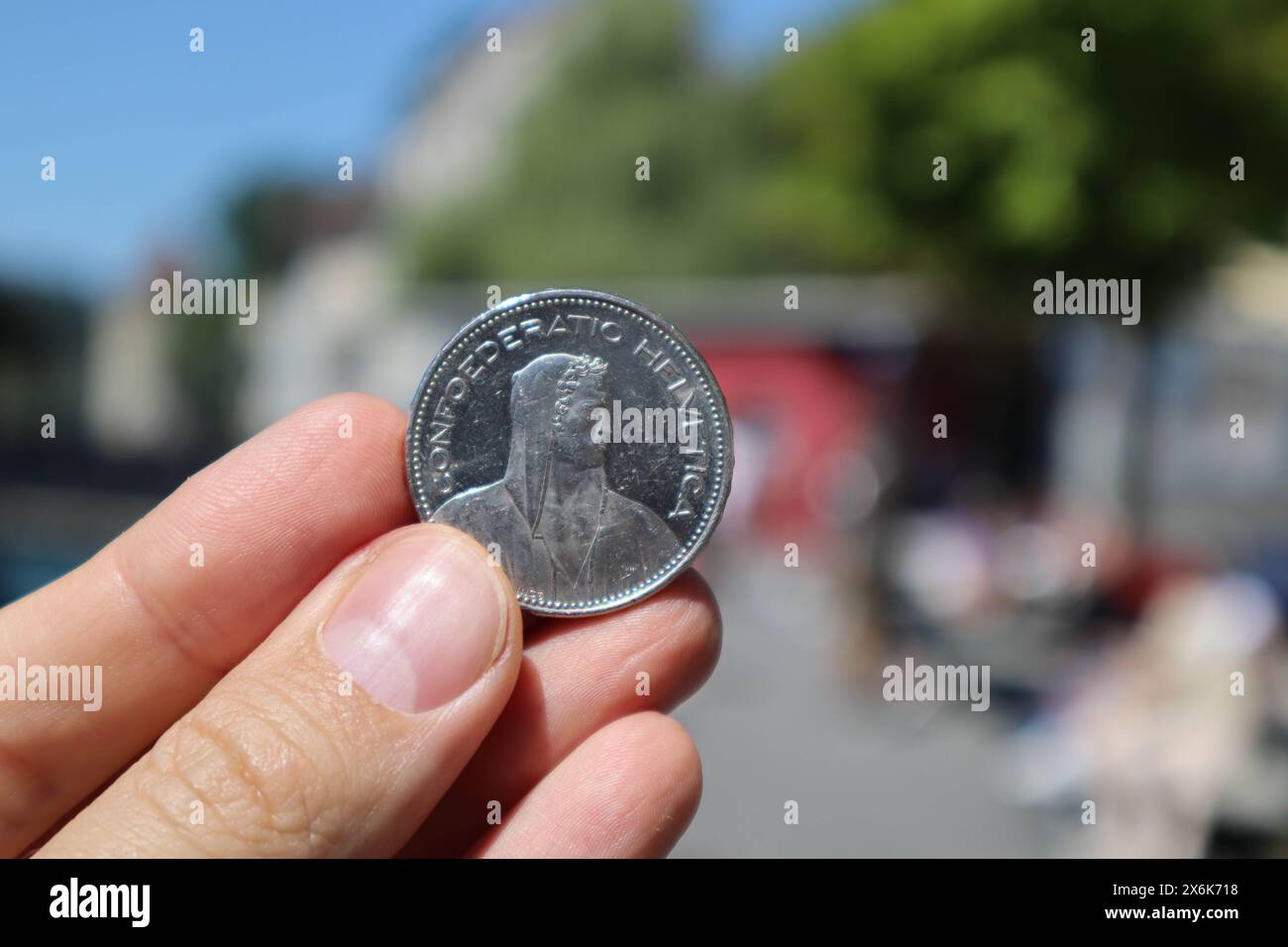 Primo piano di una moneta da 5 franchi svizzeri tenuta dalla mano di un uomo Foto Stock