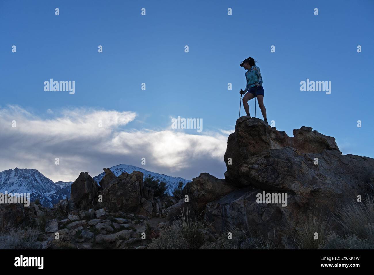 Una donna adulta attiva con pali da trekking raggiunge la cima di un ventoso Tungsten Peak nella Owens Valley vicino a Bishop California Foto Stock
