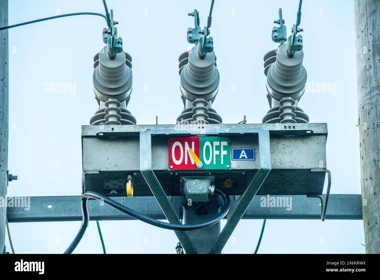 Polo del trasformatore elettrico con contrassegni “ON” e “OFF”, che evidenziano le infrastrutture rurali e i sistemi essenziali di distribuzione dell’energia. Foto Stock