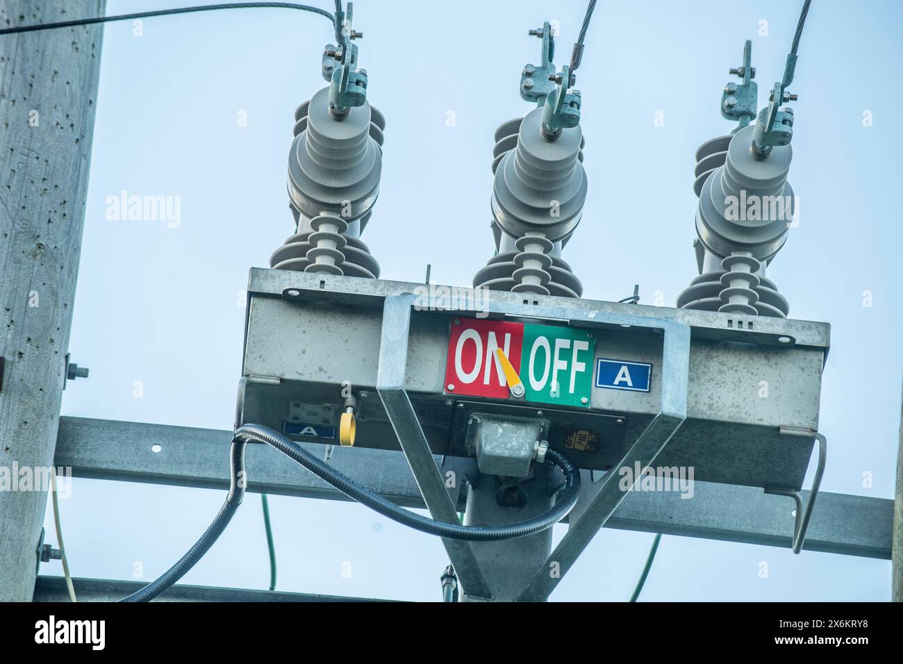 Polo del trasformatore elettrico con contrassegni “ON” e “OFF”, che evidenziano le infrastrutture rurali e i sistemi essenziali di distribuzione dell’energia. Foto Stock