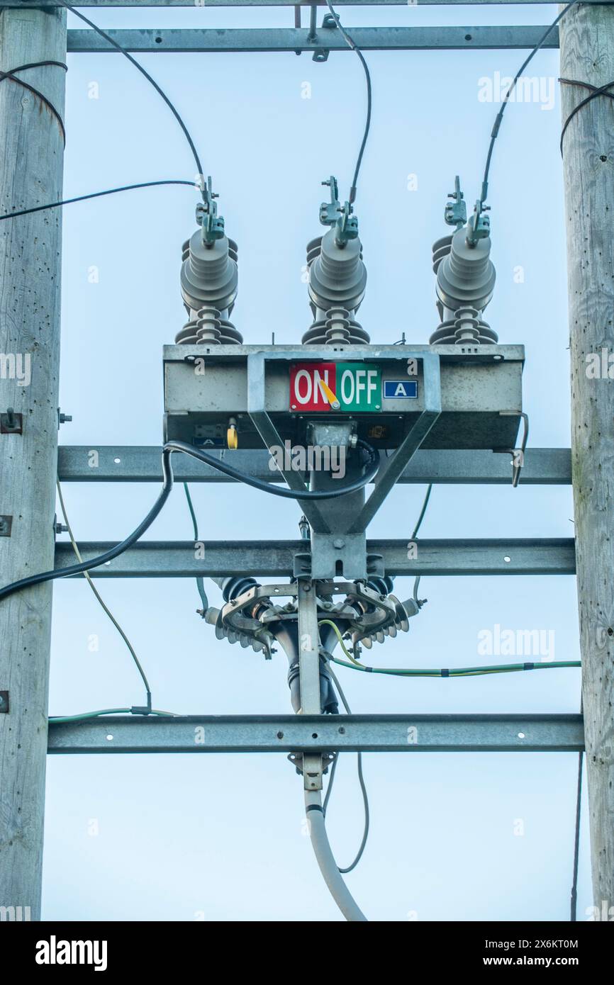Polo del trasformatore elettrico con contrassegni “ON” e “OFF”, che evidenziano le infrastrutture rurali e i sistemi essenziali di distribuzione dell’energia. Foto Stock