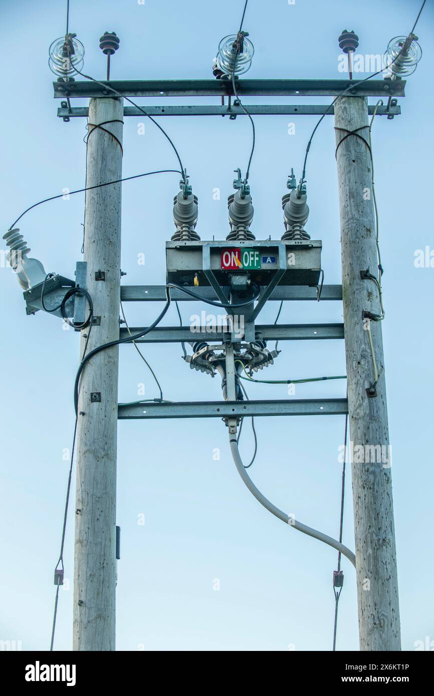 Polo del trasformatore elettrico con contrassegni “ON” e “OFF”, che evidenziano le infrastrutture rurali e i sistemi essenziali di distribuzione dell’energia. Foto Stock