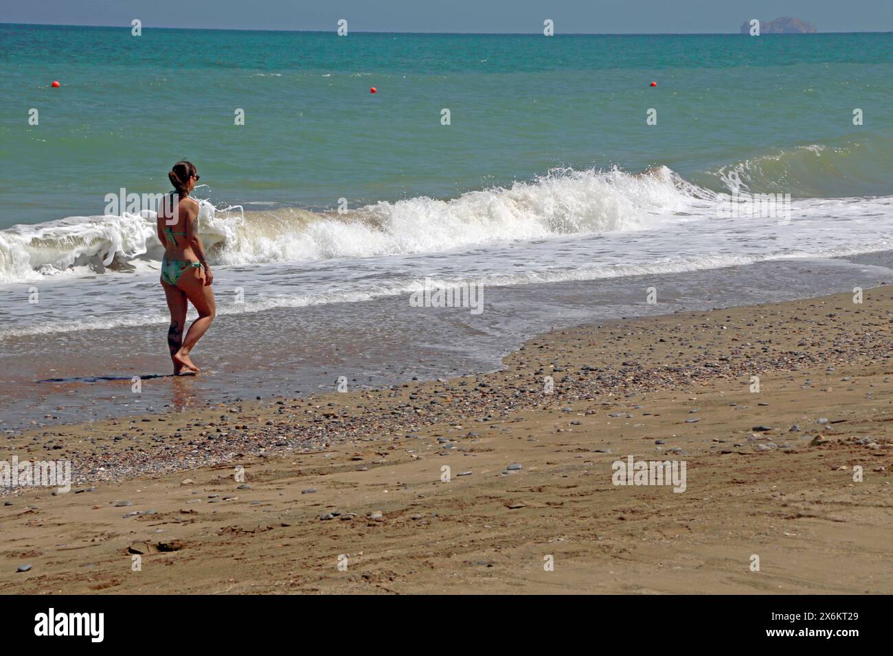 Lone Tourist che cammina lungo la costa presso il Chedi Hotel Beach Muscat Oman Foto Stock