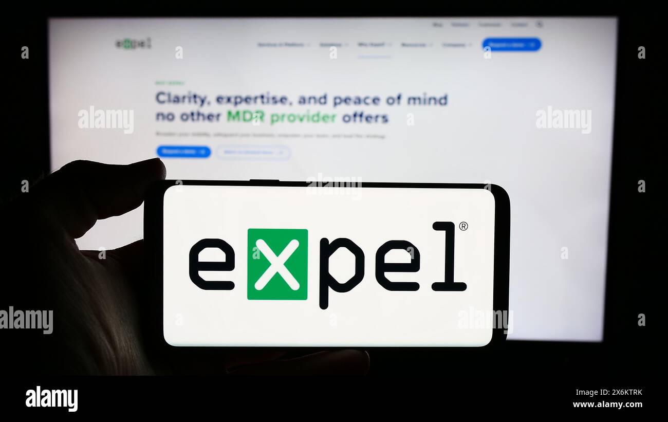 Persona che detiene un cellulare con il logo della società statunitense di sicurezza informatica Expel Inc. Di fronte alla pagina Web aziendale. Mettere a fuoco il display del telefono. Foto Stock