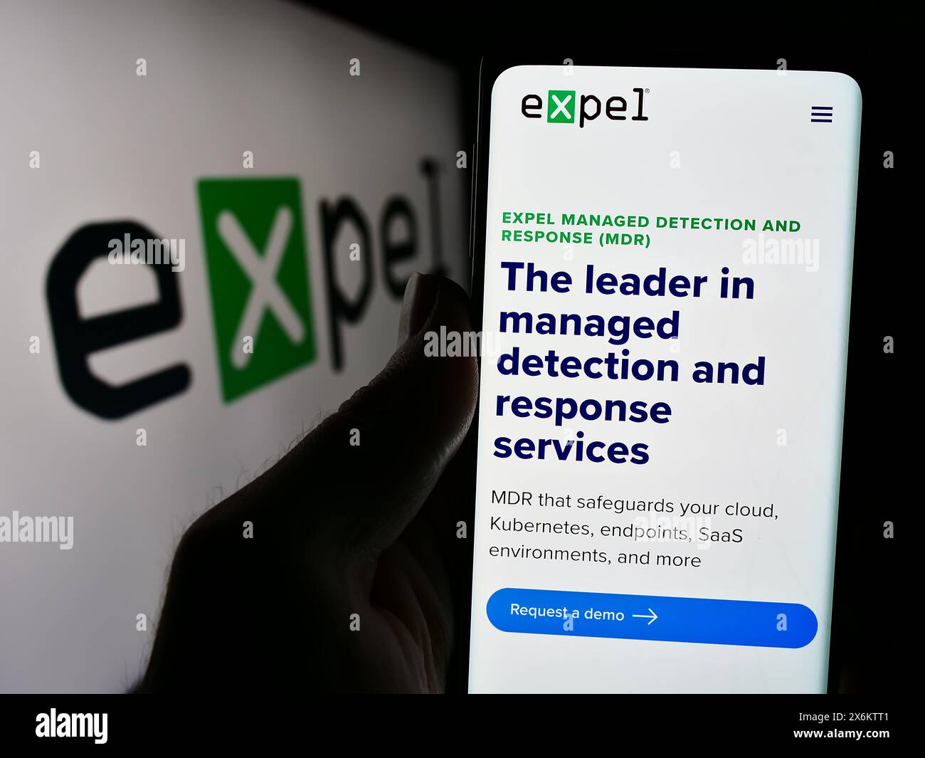 Persona che detiene un cellulare con una pagina Web della società statunitense di sicurezza informatica Expel Inc. Davanti al logo aziendale. Messa a fuoco al centro del display del telefono. Foto Stock