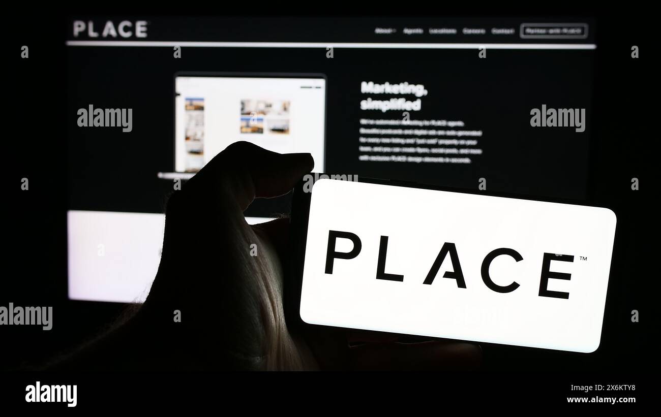 Persona che possiede un telefono cellulare con il logo della società di servizi immobiliari Place Real Estate Inc. Di fronte alla pagina Web. Mettere a fuoco il display del telefono. Foto Stock