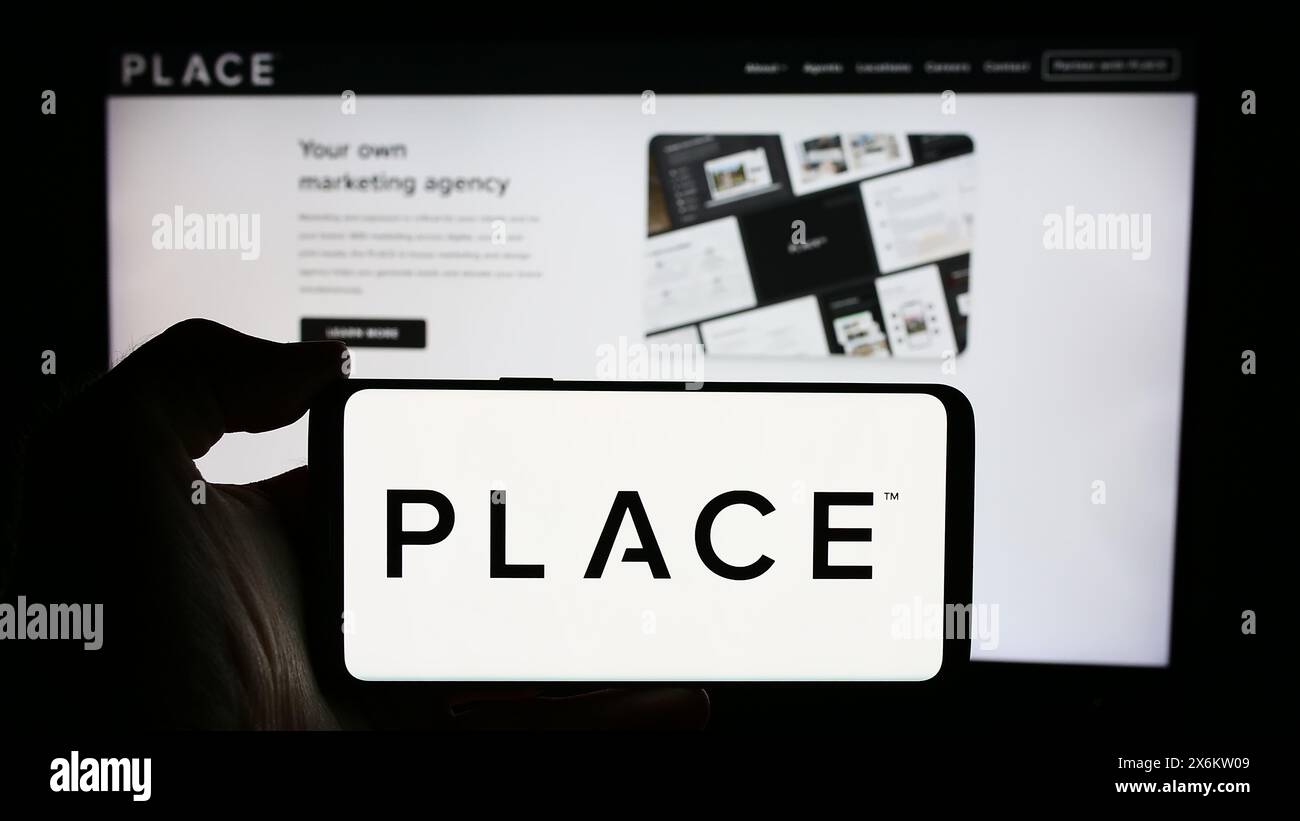Persona che detiene un cellulare con il logo della società di servizi immobiliari Place Real Estate Inc. Di fronte alla pagina web. Mettere a fuoco il display del telefono. Foto Stock