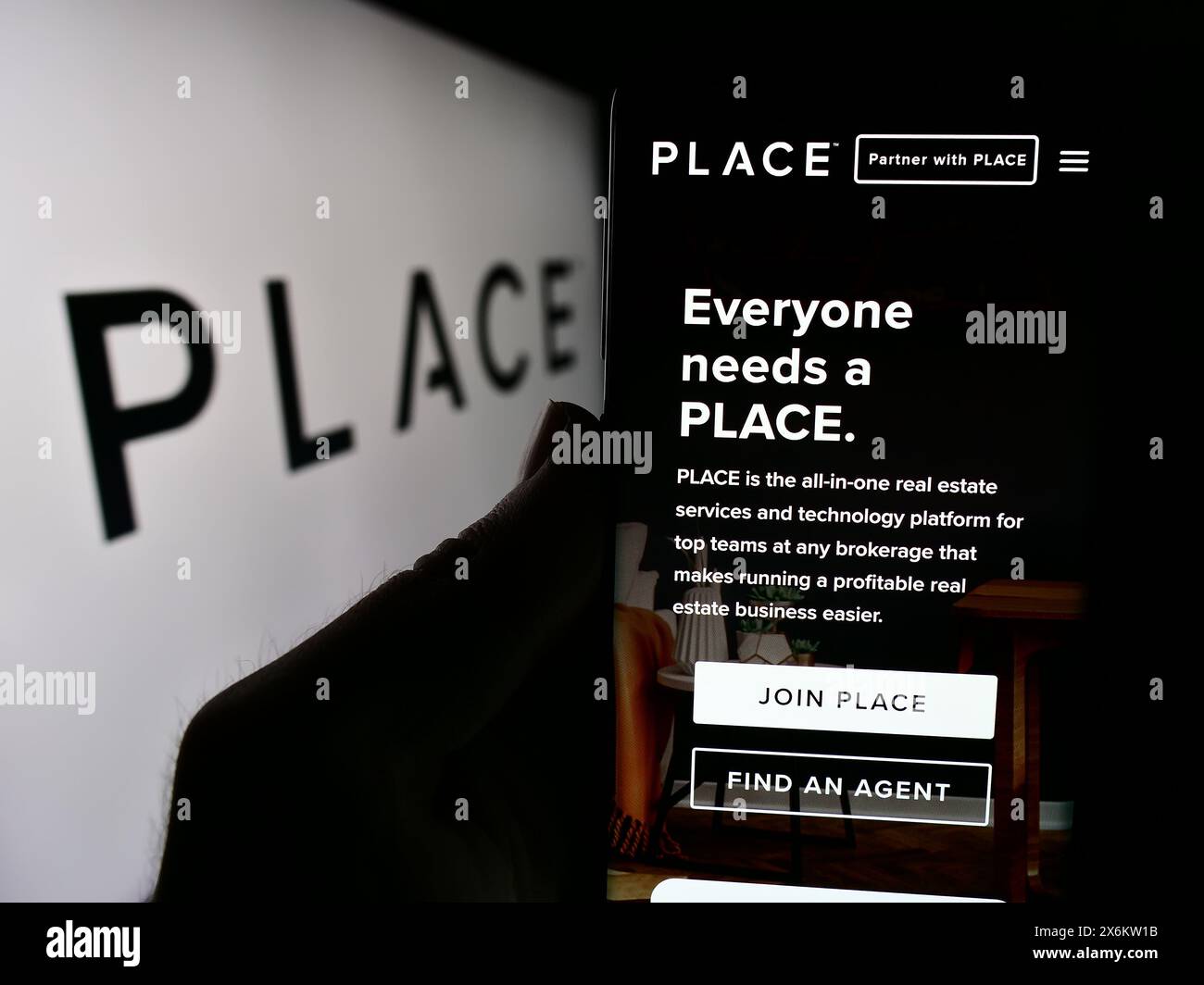 Persona che detiene un cellulare con pagina web della società di servizi immobiliari Place Real Estate Inc. Con logo. Messa a fuoco al centro del display del telefono. Foto Stock
