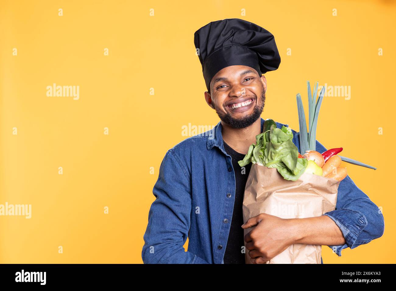 Chef afroamericano maschile che acquista alimentari freschi per preparare una speciale ricetta vegana, sentendosi entusiasta dello stile di vita sostenibile e di mangiare sano con cibo di origine etica. Zero sprechi. Foto Stock
