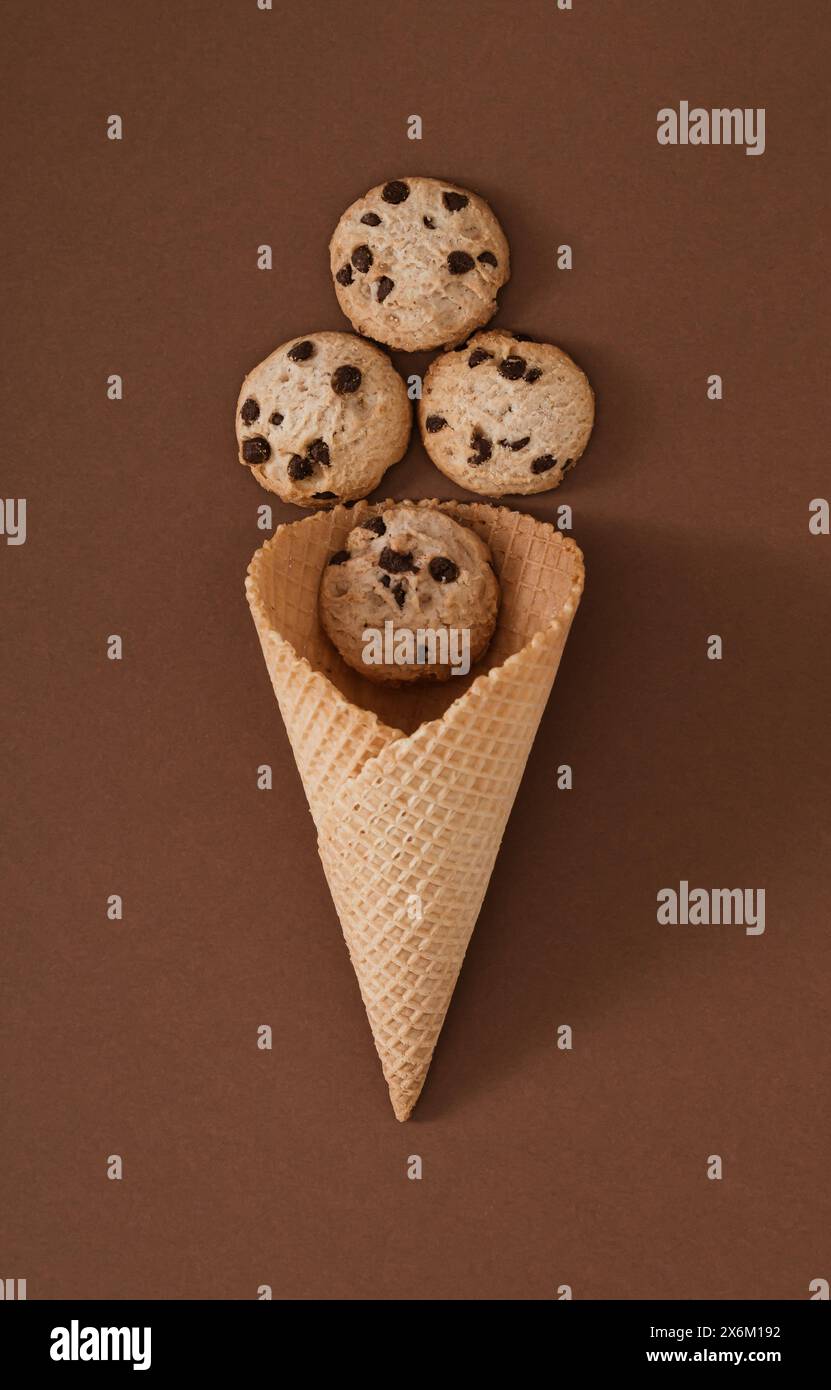 Cono gelato con biscotti al cioccolato su sfondo marrone. Concetto minimale di Sweet food. Un'idea creativa estiva. Ottima disposizione dei biscotti al cioccolato. Foto Stock