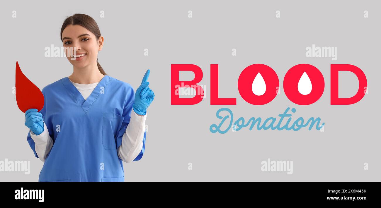 Striscione per la giornata mondiale dei donatori di sangue con una giovane infermiera che tiene una goccia di carta Foto Stock