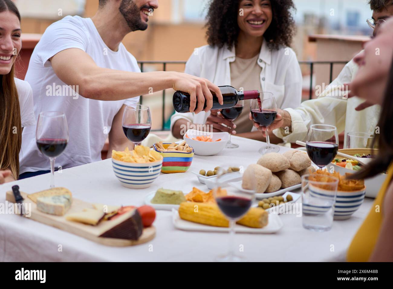Foto di un tavolo con cibo e bevande alcoliche dove un gruppo di persone irriconoscibili Foto Stock