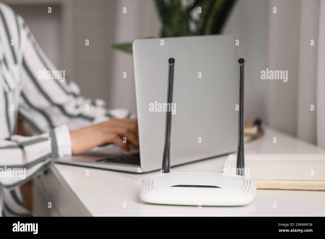 Moderno router wi-fi su un tavolo di donna che lavora con un laptop, primo piano Foto Stock