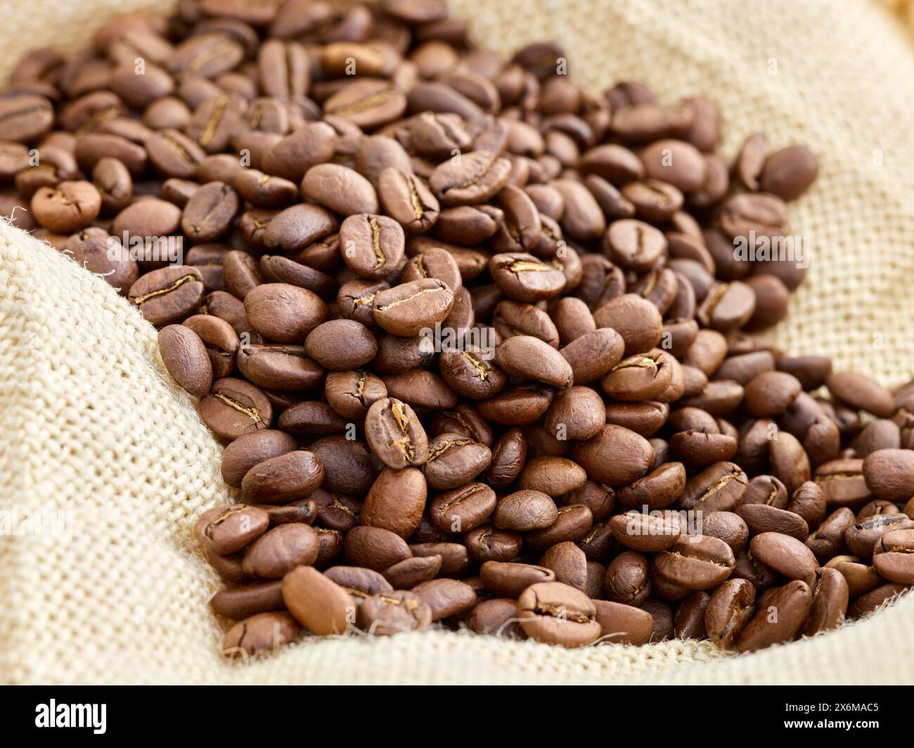 Chicchi di caffè interi su tessuto di iuta Foto Stock