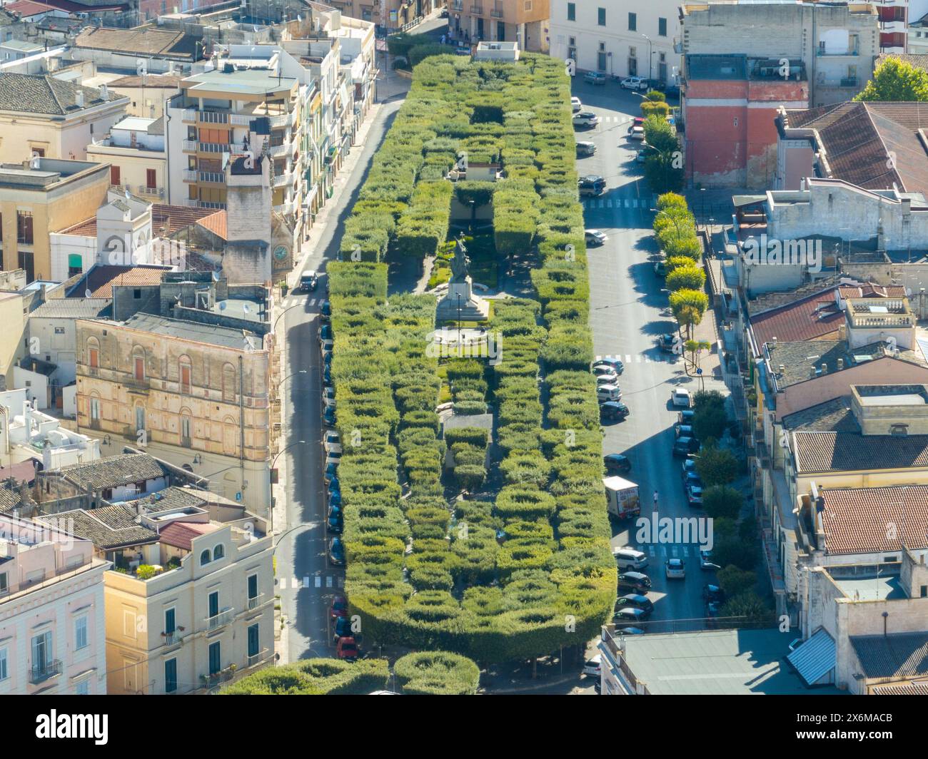 Gravina, Italia - 8 agosto 2023: La villa comunale della città con il monumento alla guerra. Le aiuole di fiori e il prato del giardino ben tenuto nel parco. Foto Stock