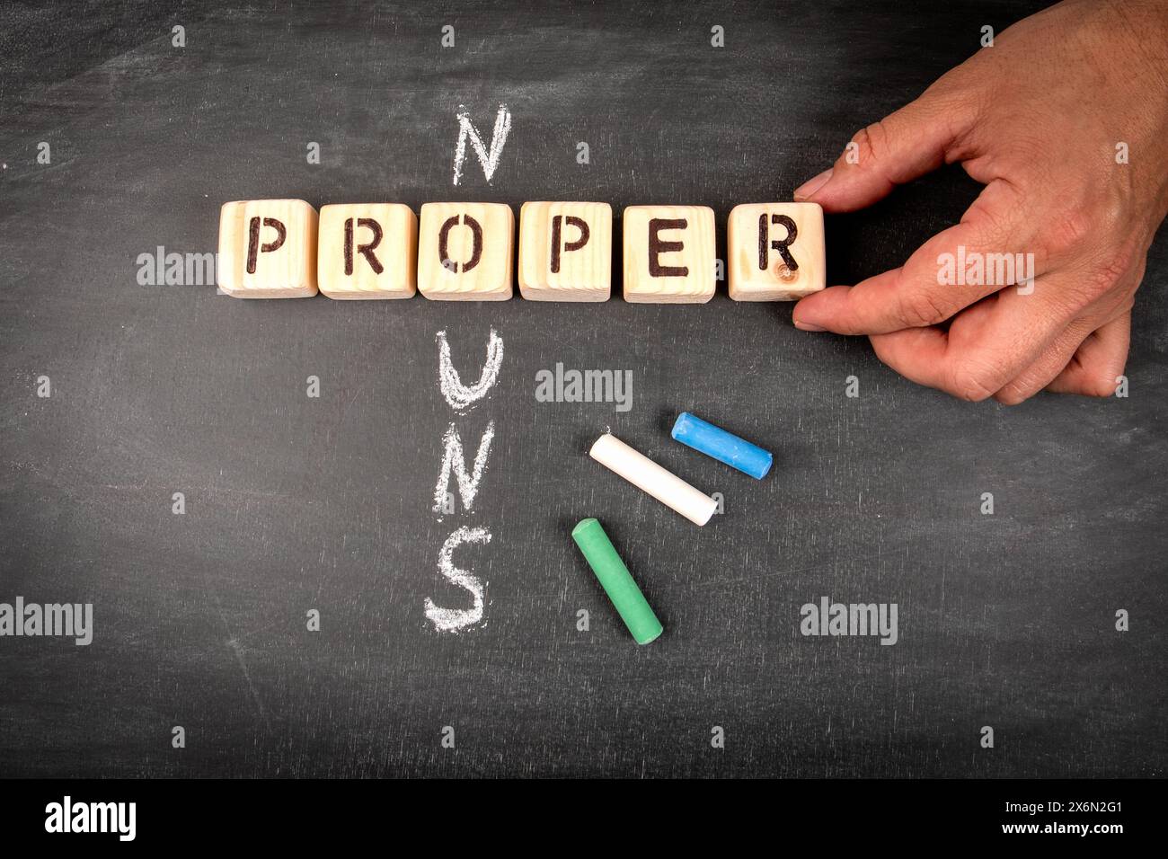 Nomi veri. Puzzle a croce con blocchi di legno e pezzi di gesso su uno sfondo di lavagna. Foto Stock