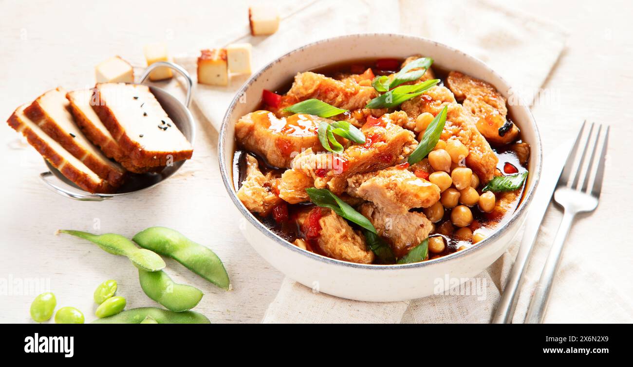 Soia con carne di soia, cipolla e tofu su sfondo di legno chiaro. Cibo vegano. Vista dall'alto, banner Foto Stock