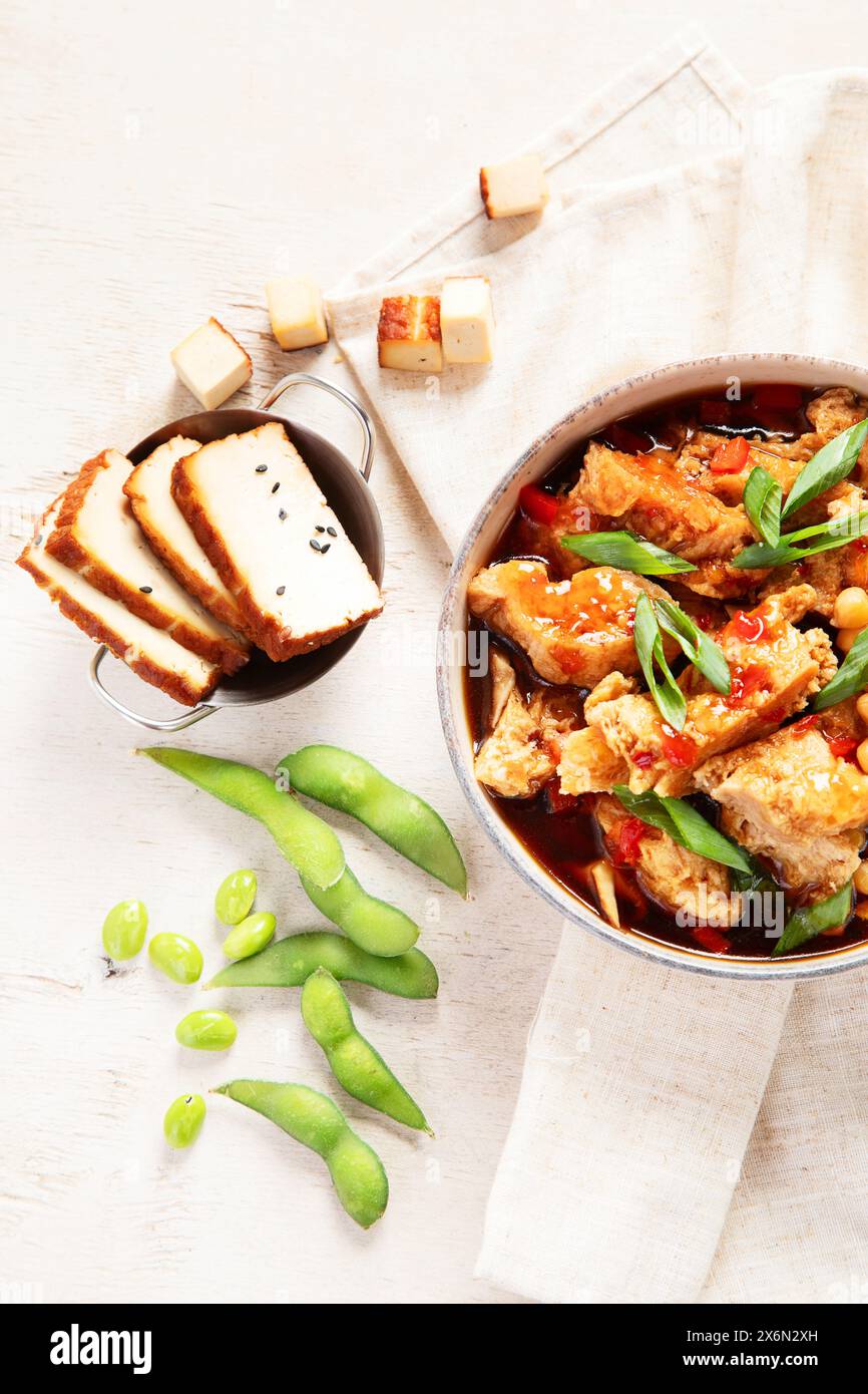 Soia con carne di soia, cipolla e tofu su sfondo di legno chiaro. Cibo vegano. Vista dall'alto Foto Stock