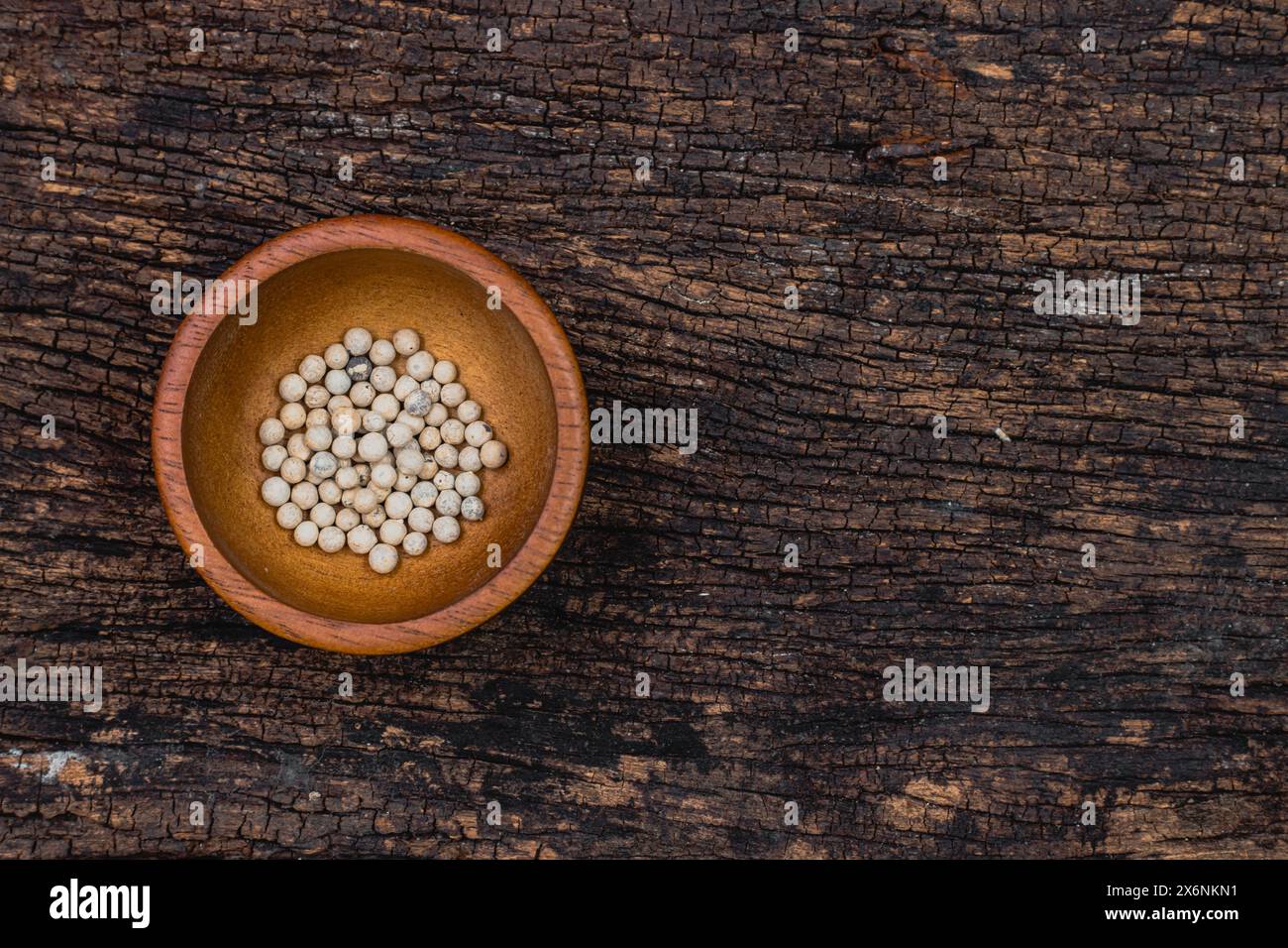 Ingrediente aromatico caldo e piccante con semi di pepe bianco essiccati su sfondo in legno vecchio con spazio per la vista dall'alto del testo piatto Foto Stock