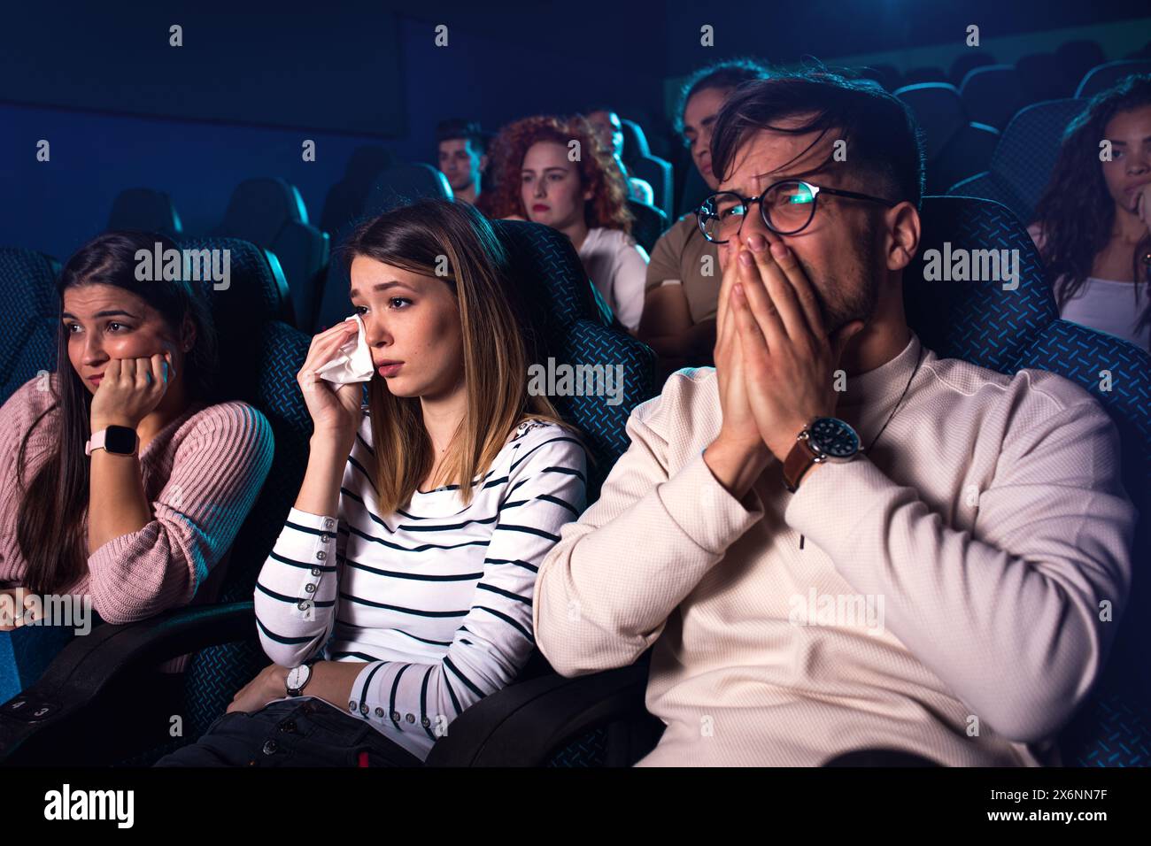 Gruppo di persone che guardano film tristi al cinema. Foto Stock