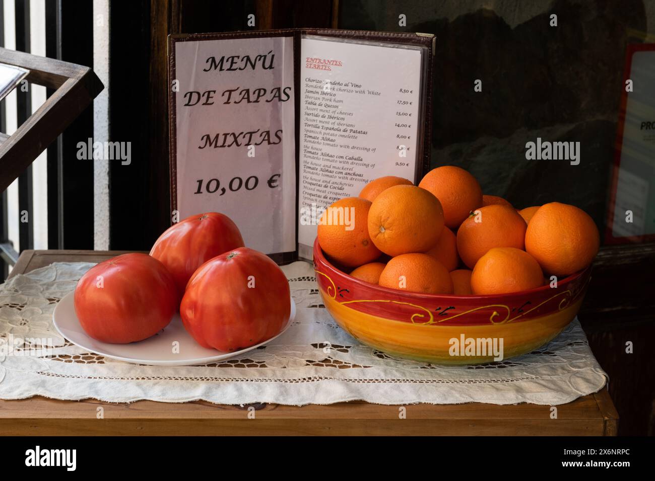 Immagine della natura morta di una ciotola di tomati e arance e un menu di tapas che invitano i clienti a cenare in un ristorante nel sud della Spagna. Foto Stock