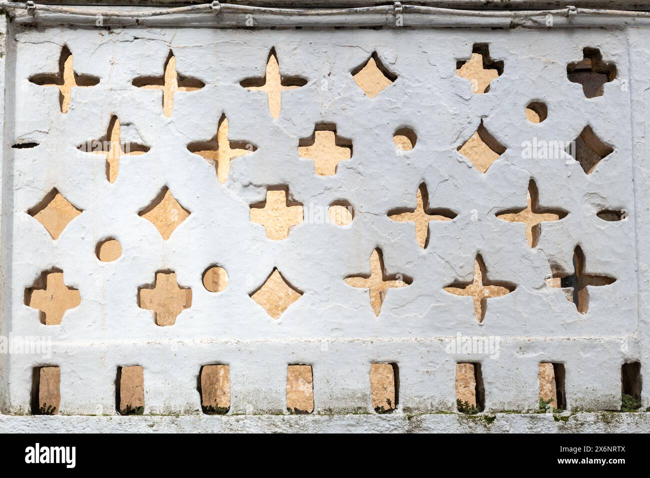 Parete imbiancata in Spagna con intagli di varie forme, dimensioni e simboli. Foto Stock