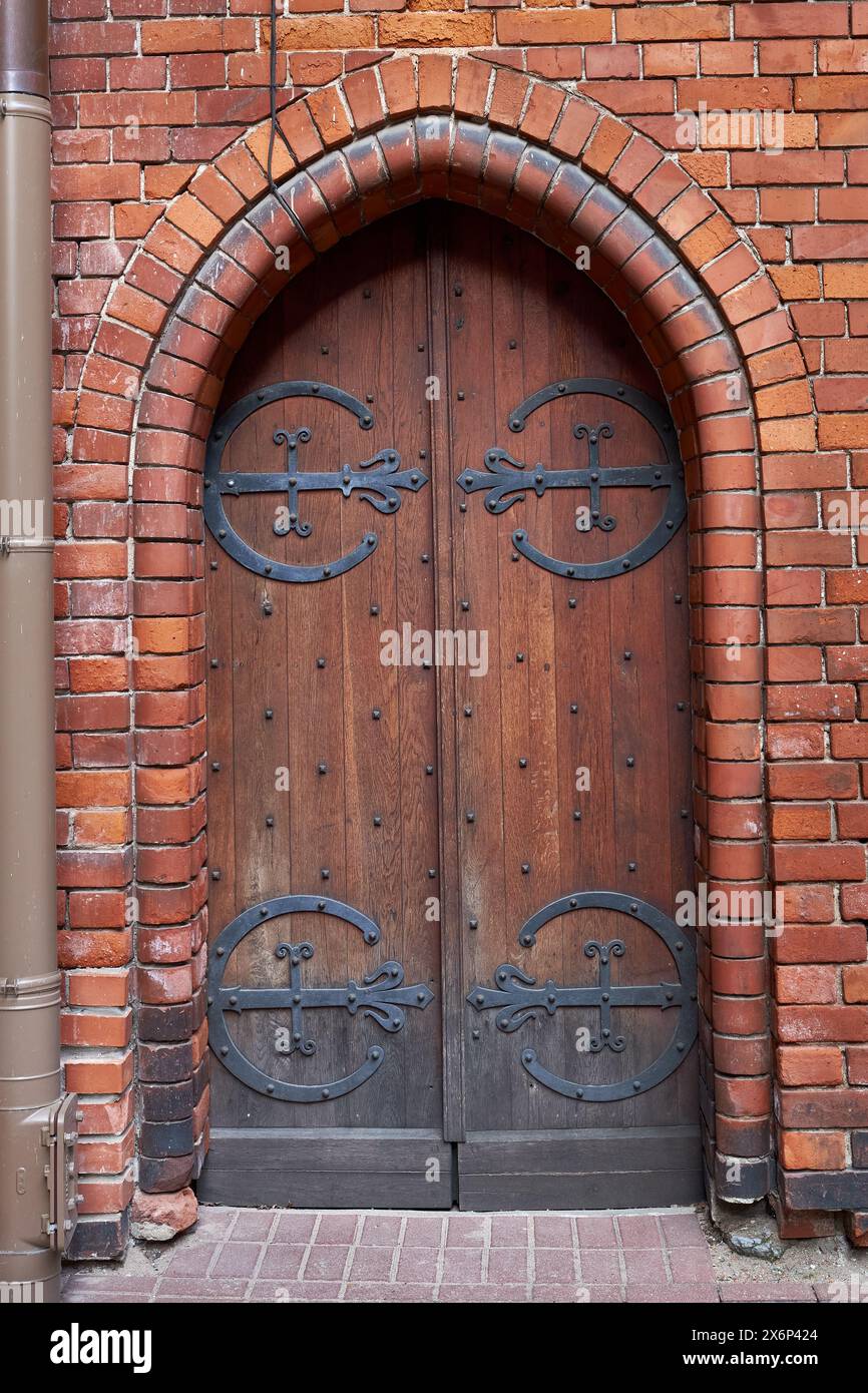 Vecchia porta gotica in legno d'epoca su una facciata di un edificio medievale in mattoni. Foto Stock