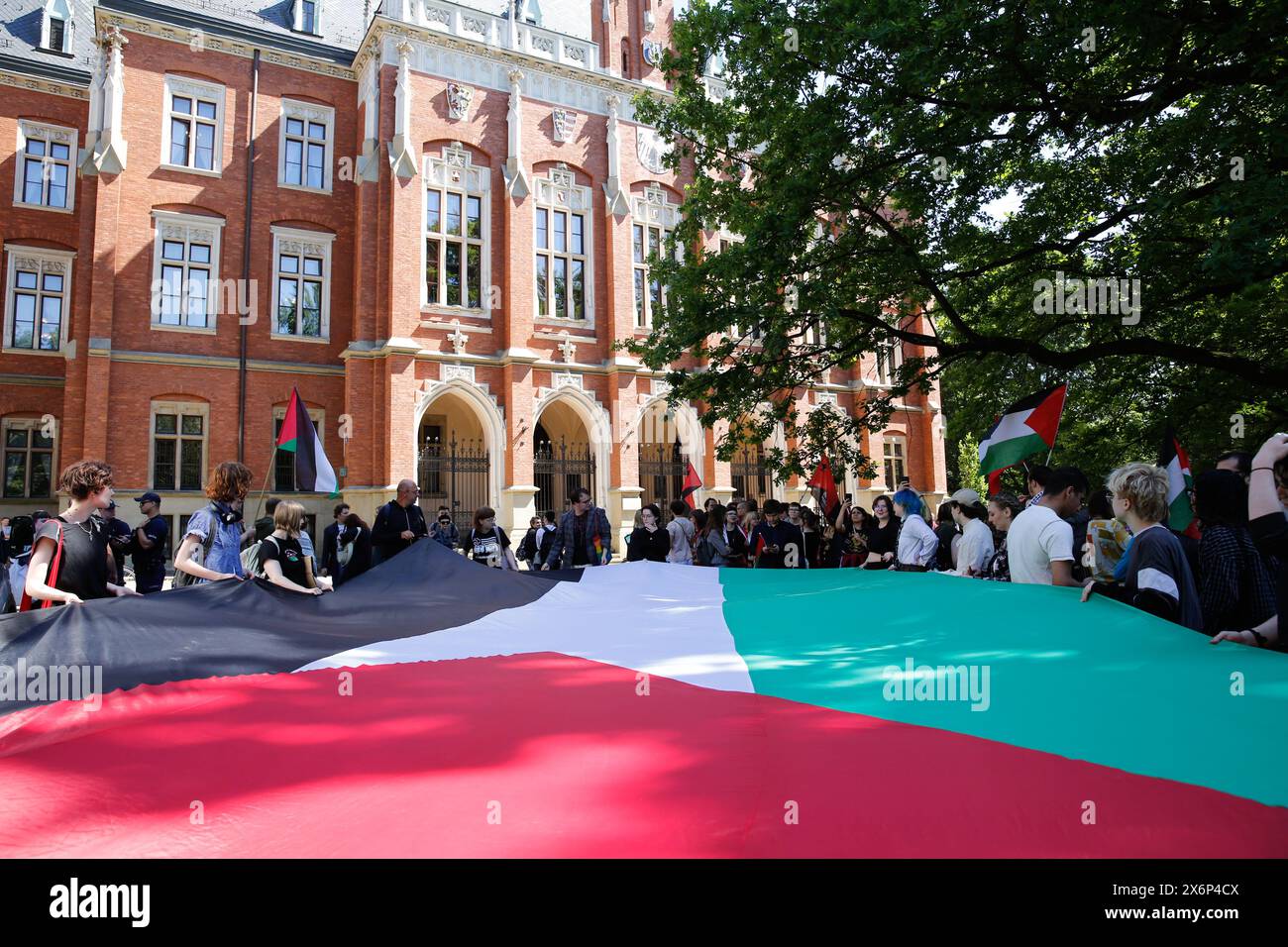 Gli studenti cantano slogan pro-Palestina e tengono bandiere e striscioni palestinesi durante la prima manifestazione in Polonia organizzata da studenti e studiosi contro l'attacco israeliano alla Striscia di Gaza di fronte al Collegium Novum, l'ufficio del preside dell'Università Jagellonica a Cracovia, Polonia, il 15 maggio 2024. Foto Stock