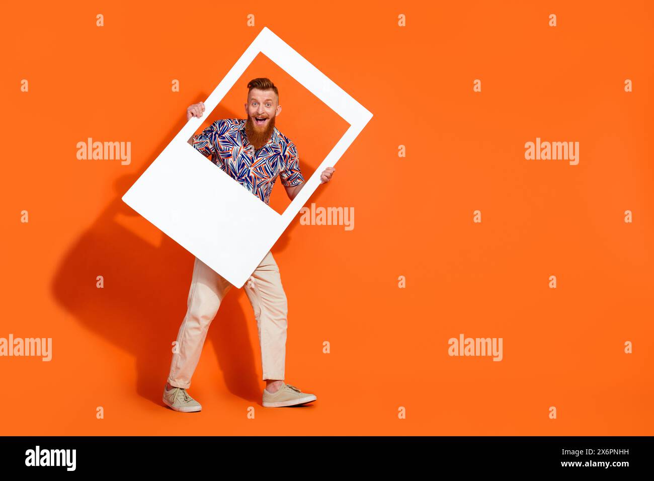 Foto a grandezza naturale dell'eccentrico uomo felicissimo indossa eleganti pantaloni bianchi con montatura bianca isolata su sfondo arancione Foto Stock