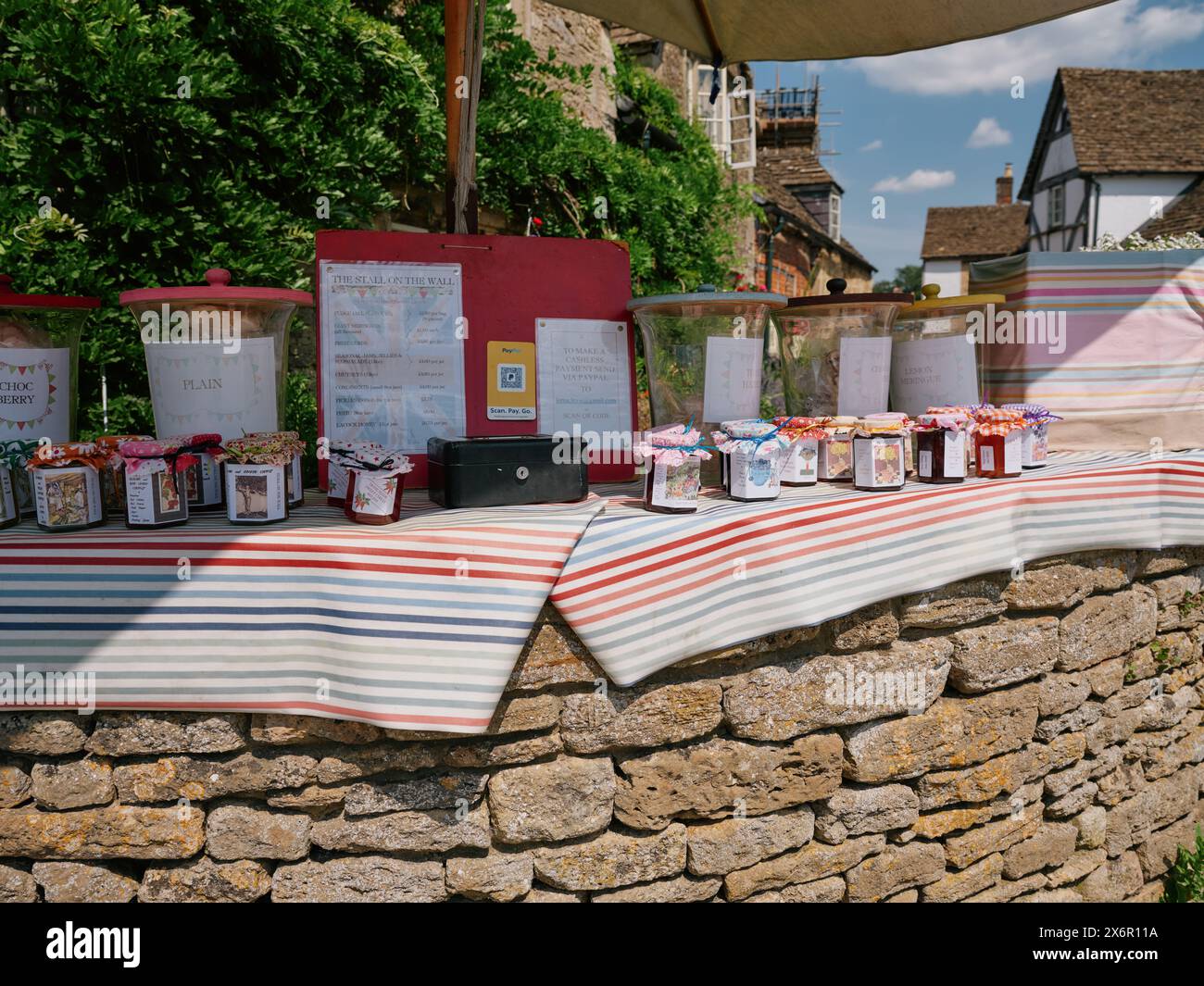 Bancarelle di prodotti locali con barattoli di marmellata e chutney fatti in casa in vendita con una scatola onestà in un villaggio inglese estivo, Inghilterra Regno Unito - vita da villaggio Foto Stock