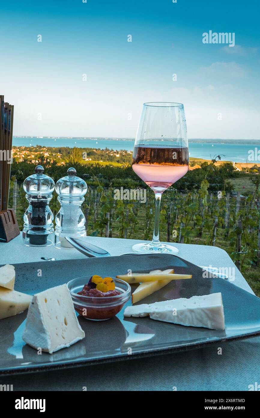 Vino, tavolo di formaggi sul lago Balaton sulla collina cena, pranzo, data romantica, picnic, mangiare sulla natura. Ristorante con vini Csopak al crepuscolo Foto Stock