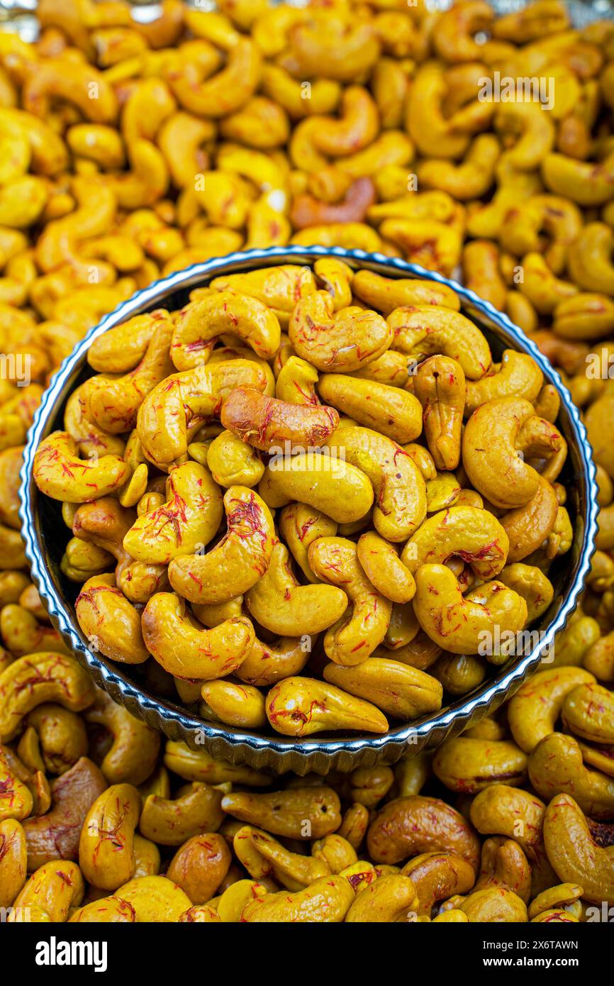 Primo piano di anacardi allo zafferano in una ciotola decorativa, Un'immagine ad alta risoluzione che mostra anacardi infusi di zafferano in una ciotola decorativa blu e bianca. Foto Stock