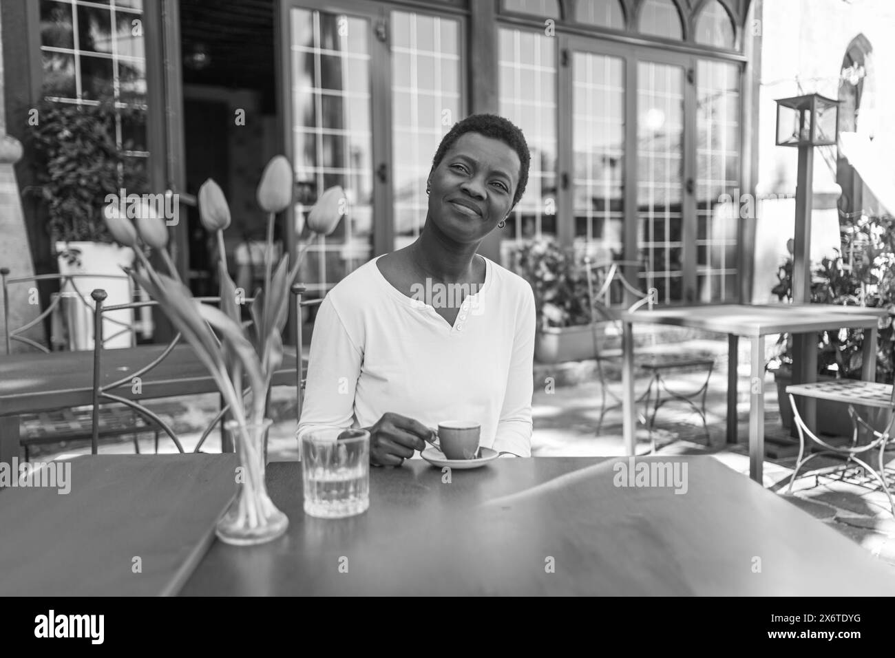 Uomo in un abbigliamento informale che si gusta un drink da una tazza di caffè rosso in una caffetteria all'aperto Foto Stock