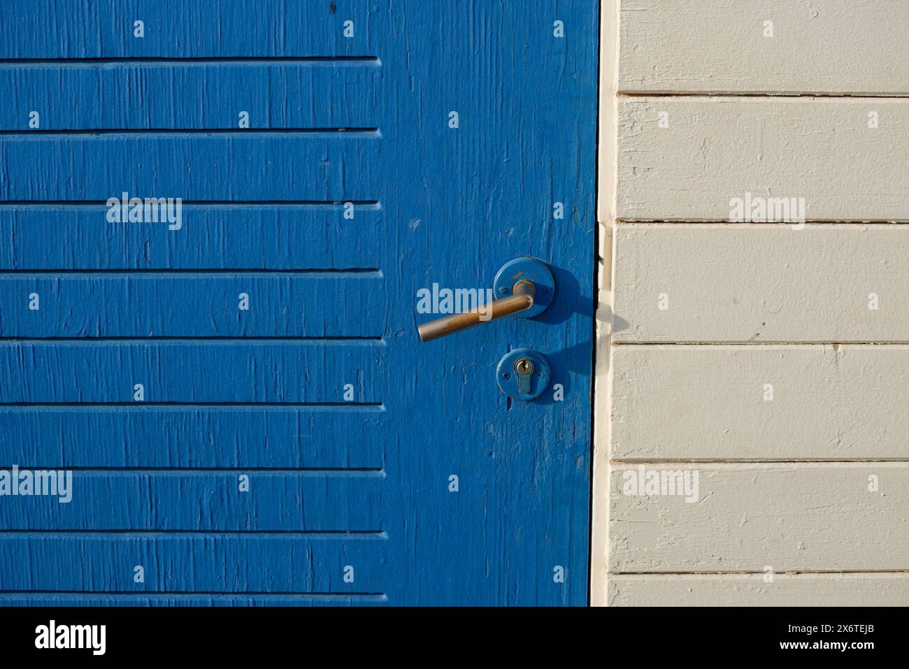 Vecchie superfici in legno verniciato sbiadito. Sportello e maniglia blu. Foto Stock