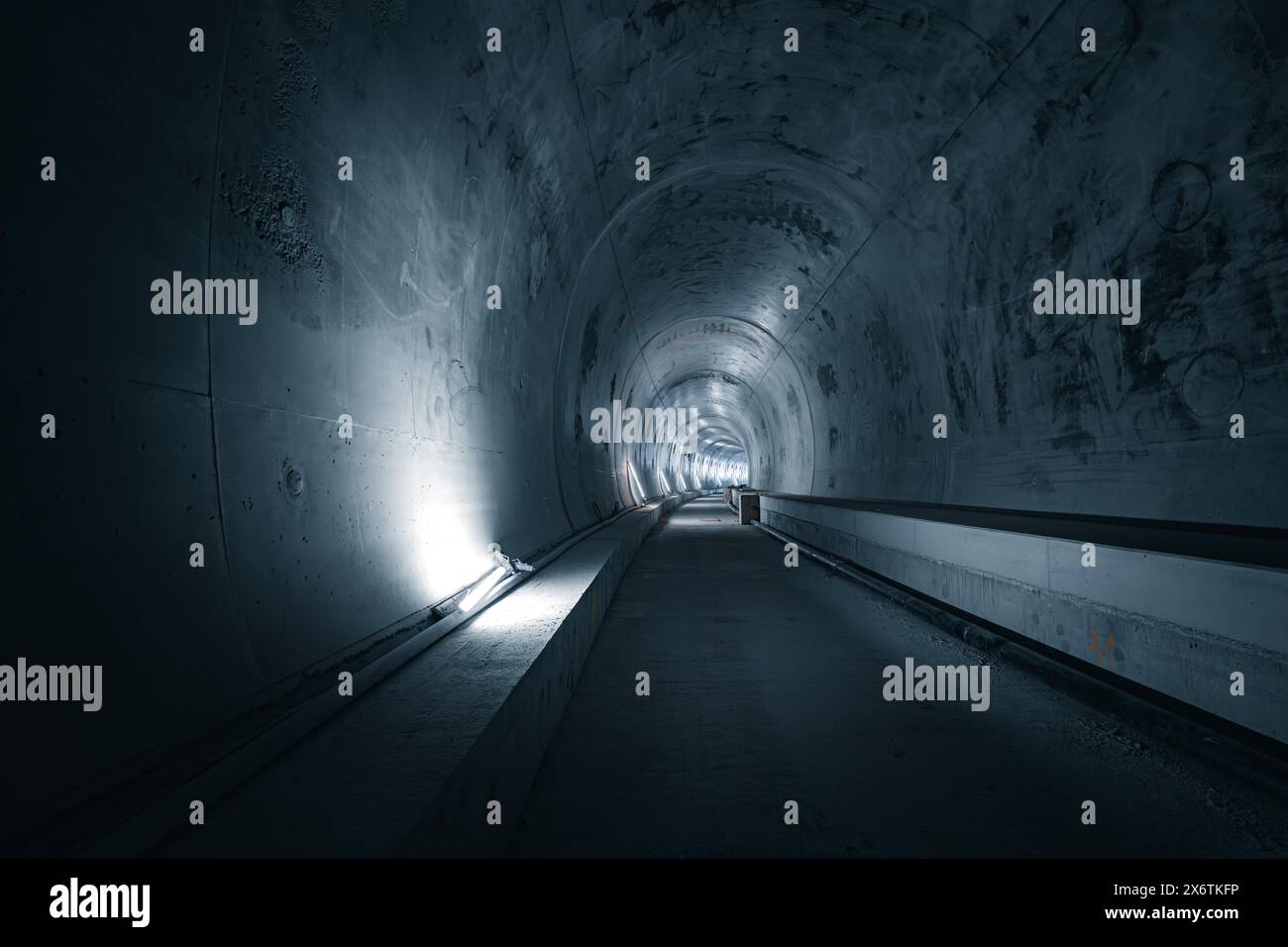 Un lungo tunnel con pareti in cemento e luci a LED sui lati che creano un'atmosfera buia e industriale, Tunnelbau Hermann Hesse Bahn, Ostelsheim Foto Stock