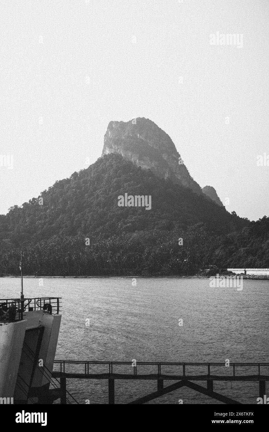 La tranquilla maestosità di una formazione rocciosa di montagna avvolta nella nebbia e in bianco e nero. Surat Thani, Thailandia Foto Stock