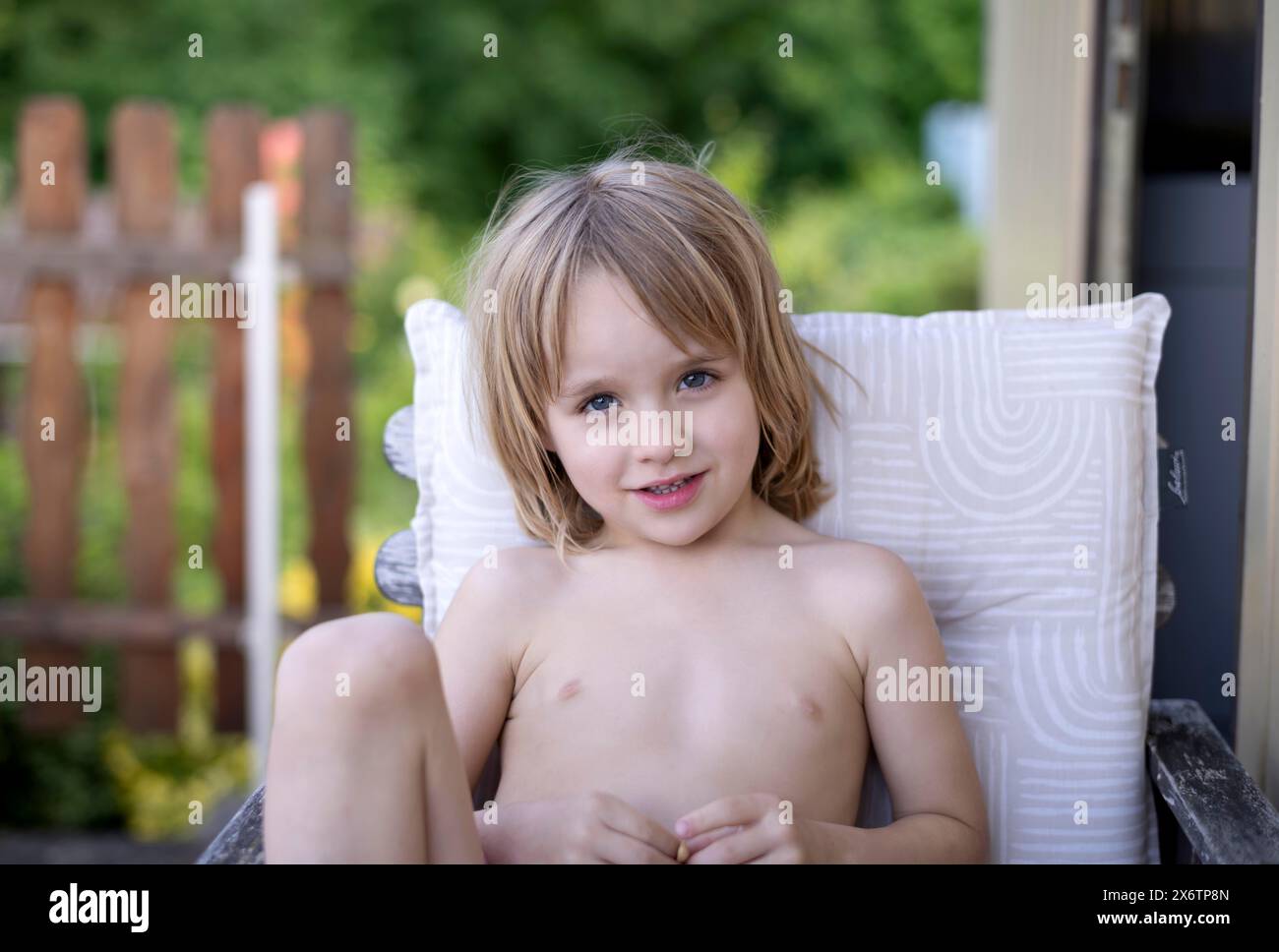 Ragazzo, 5 anni, biondo, seduto su una sedia da giardino, giardino, estate, Stoccarda, Baden-Wuerttemberg, Germania Foto Stock