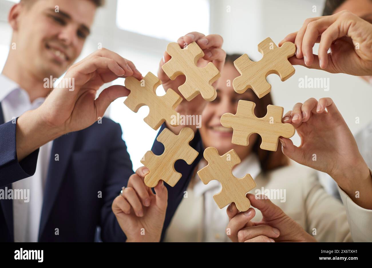 Gruppo di uomini d'affari che assemblano puzzle in ufficio. Concetto di cooperazione e supporto al lavoro di squadra. Foto Stock