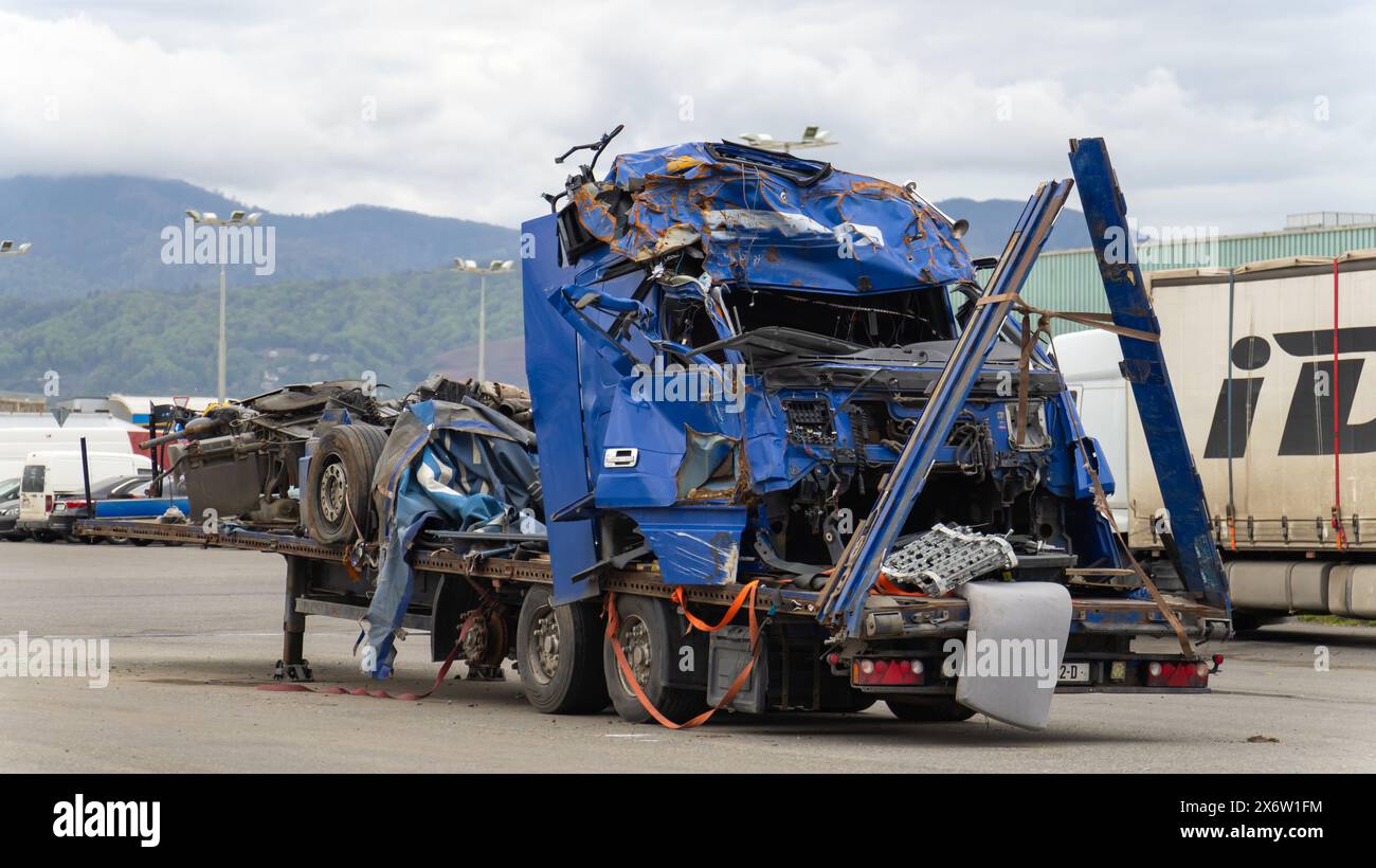Cabina motrice blu ammaccata e semirimorchio su una piattaforma di traino nel parcheggio dopo un grave incidente. Foto Stock