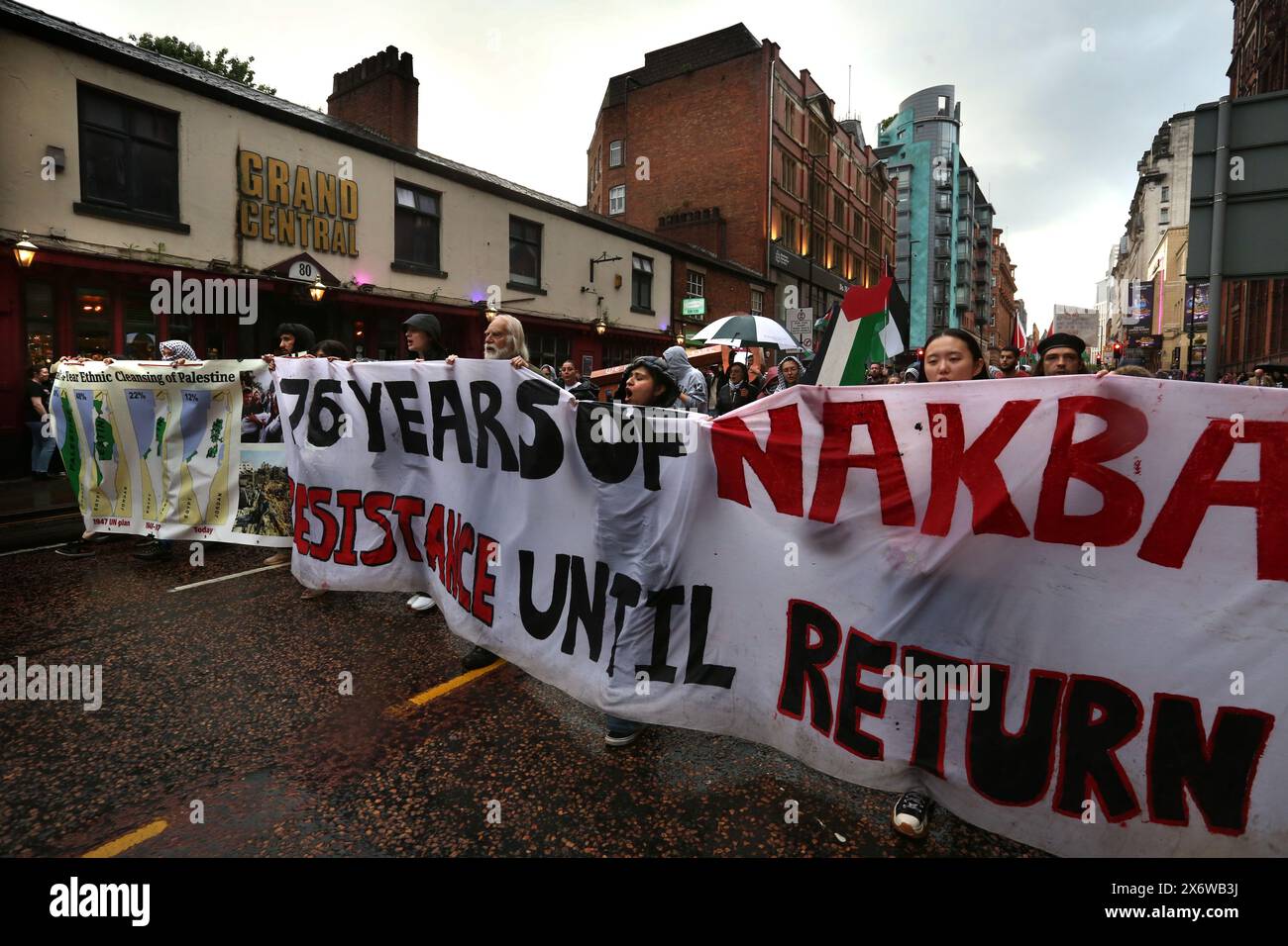 I manifestanti marciano nel centro di Manchester sulla strada dietro un grande cartello che dice "76 anni di resistenza Nakba fino al ritorno". I manifestanti si recano per le strade di Manchester per commemorare il 76° anniversario della Nakba (la catastrofe), quando nel 1948 oltre 700.000 palestinesi sono fuggiti o sono stati espulsi dalle loro case e terre dai paramilitari e dallo Stato israeliano. Quella popolazione e i loro decenti hanno vissuto in esilio e promettono un giorno di ritorno. Finiscono il raduno all’Università di Manchester, dove gli studenti e i loro sostenitori hanno istituito un campo di resistenza contro quello dell’università Foto Stock