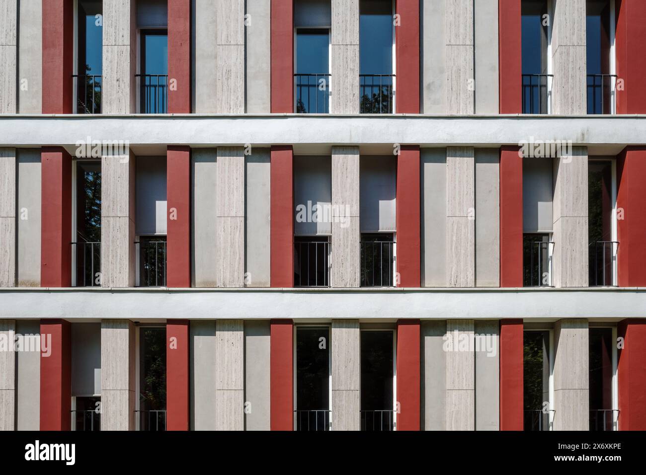 Una facciata moderna di un edificio caratterizzato da un design simmetrico con strisce verticali alternate in tonalita' rosse e beige. Foto Stock