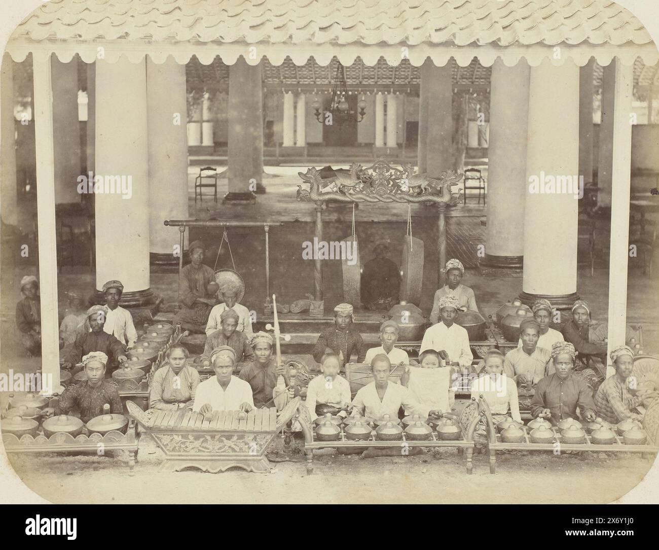 Orchestra gamelan, Un'orchestra gamelan, composta da 23 persone, sedute sotto il tetto di uno spazio coperto con spesse colonne. Parte dell'album fotografico presentato dalla Soerabayasche Association of Sugar Manufacturers a Frederik Beyerinck, residente a Soerabaya., Fotografia, Herman Salzwedel, Soerabayasche Vereeniging van Suikerfabrikanten, Surabaya, 1876 - 1884, supporto fotografico, stampa albume, altezza, 21,3 cm x larghezza, 27,5 cm Foto Stock